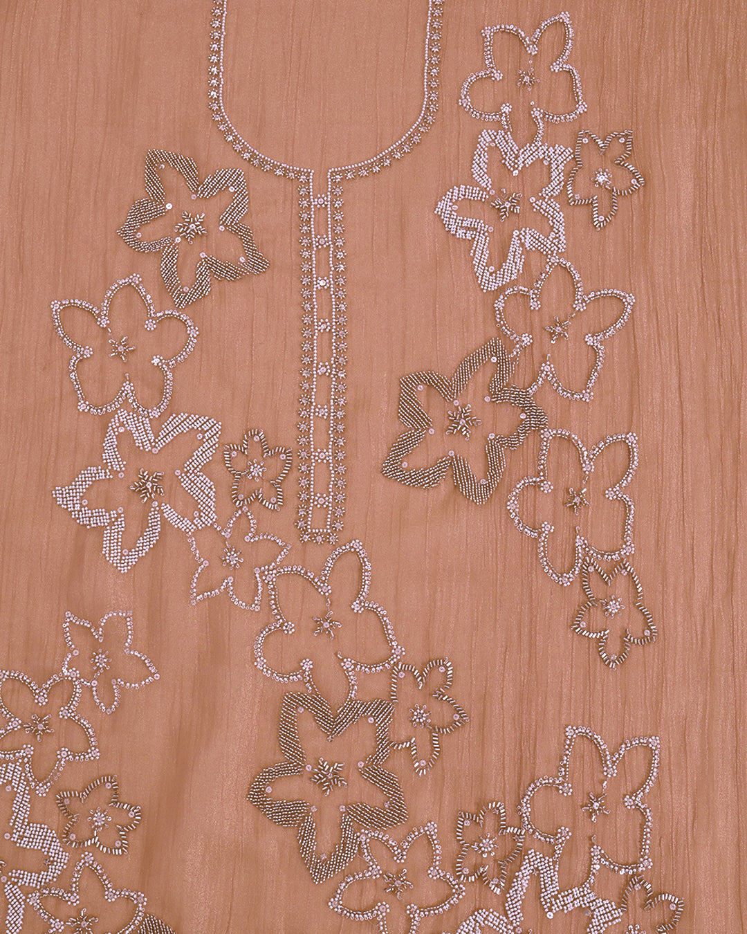 Close-up of a peach-colored fabric garment featuring intricate floral embroidery and beadwork in silver and white thread.
