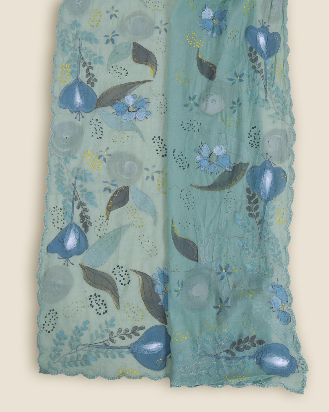 A light teal-green sheer fabric scarf or shawl with scalloped edges, decorated with a hand-painted style floral and leaf pattern in shades of blue, gray, and olive green.