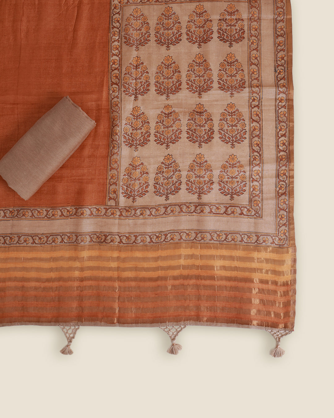 An orange and beige printed saree or fabric panel with a rolled beige cloth, displayed flat against a light cream background.