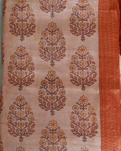 A close-up of a patterned textile or fabric panel with repeating ornate floral motifs in rust orange and brown on a warm beige background, plus a solid rust-orange border along the right edge.