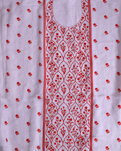 A close-up of a white fabric garment featuring red floral embroidery. The design includes a central vertical panel with an intricate repeating floral pattern bordered by red lines, and small scattered red floral motifs on the sides.