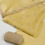 Yellow fabric with intricate embroidery and a matching clutch on a light gray background