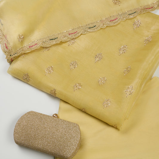 Yellow fabric with intricate embroidery and a matching clutch on a light gray background