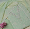 Light green fabric with floral embroidery and pink flowers on a beige background