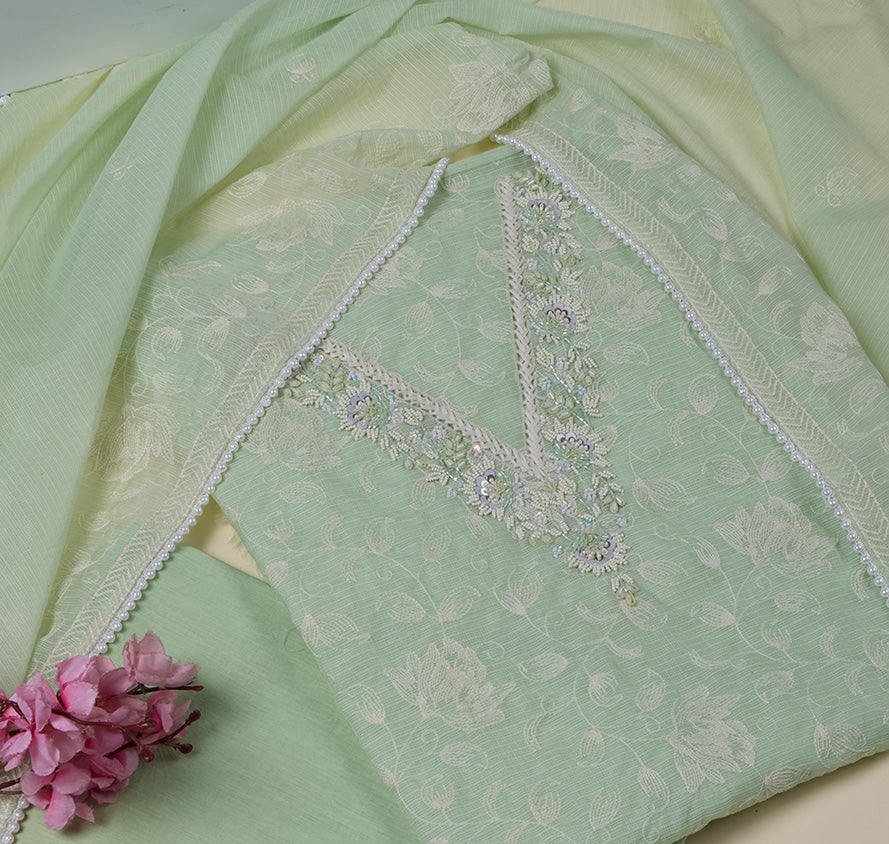 Light green fabric with floral embroidery and pink flowers on a beige background